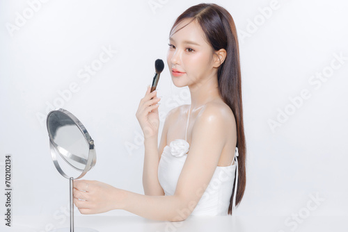 Young Asian woman long hair with clean fresh skin holding brush self makeup on white background, Female model Face care, Facial treatment, Cosmetology, beauty and spa, Asian women portrait.