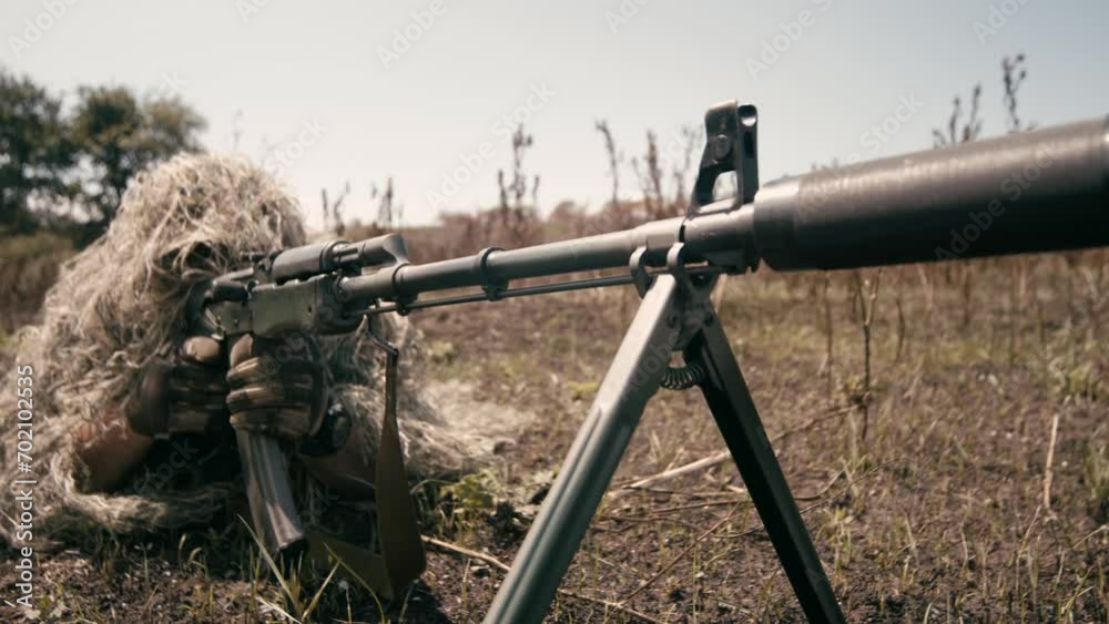 A close-up of a sniper wearing a camouflage suit or grass cloak, waiting and looking through a rifle scope. The sniper aims and shoots. Marksmanship shooting. Cinematic shot A close-up of a sniper wearing a camouflage suit or grass cloak, waiting and looking through a rifle scope. The sniper aims and shoots. Marksmanship shooting. Cinematic shot