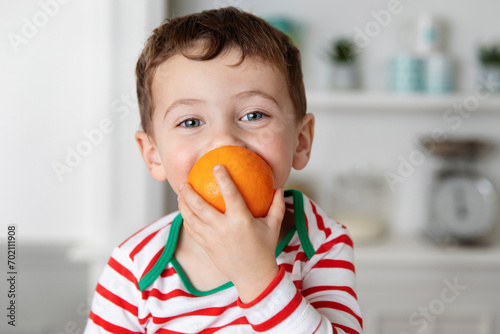 Happy little boy biting in an orange photo