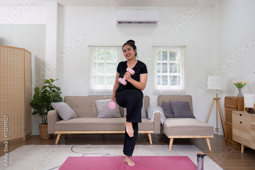 Fat woman exercising at home A beautiful oversized woman in a sports bra and casual pants stands in the living room and exercises.