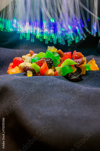 delicious multi-colored candies with nuts on a dark background with turquoise and blue luminous garlands trembling against the background close-up