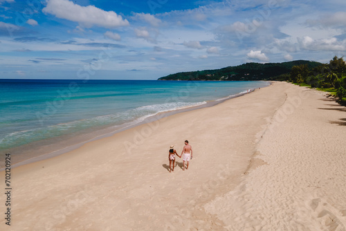 A couple of men and women relaxing on a white tropical beach with palm trees in Phuket Thailand