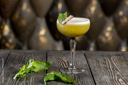 green cocktail on a wooden board with basil leaves