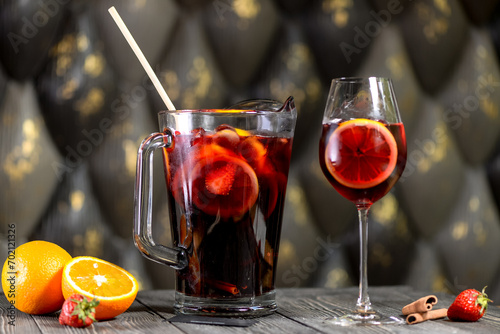 sangria in a pitcher with a glass next to it on a wooden board