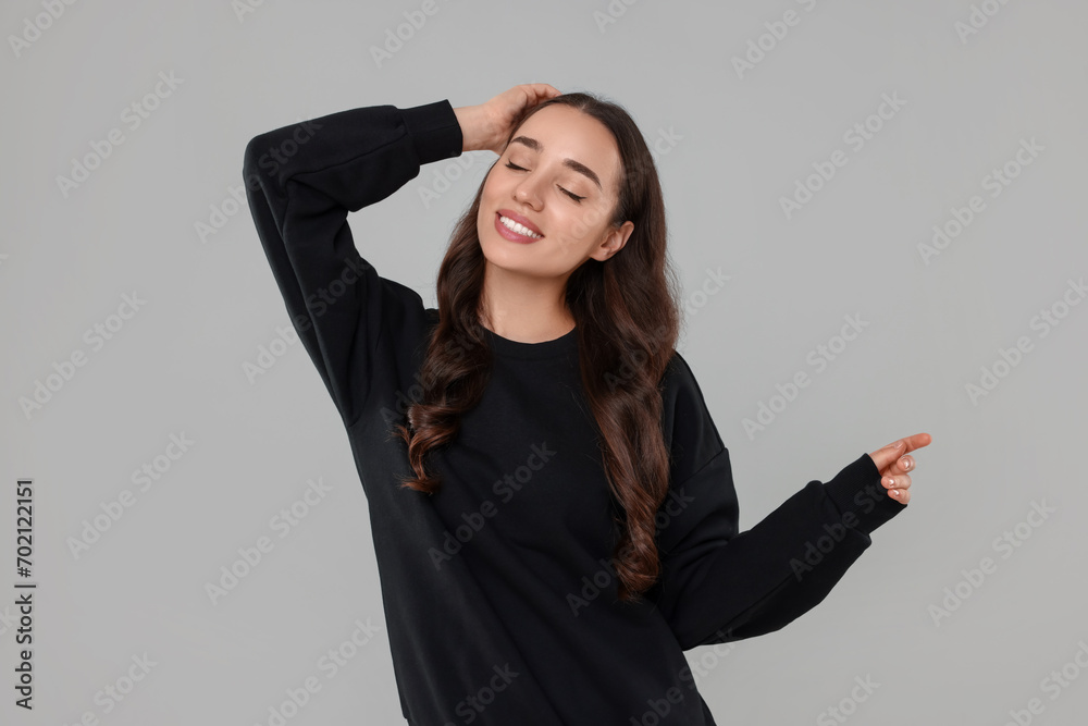 Beautiful young woman in stylish warm sweater on grey background Beautiful young woman in stylish warm sweater on grey background