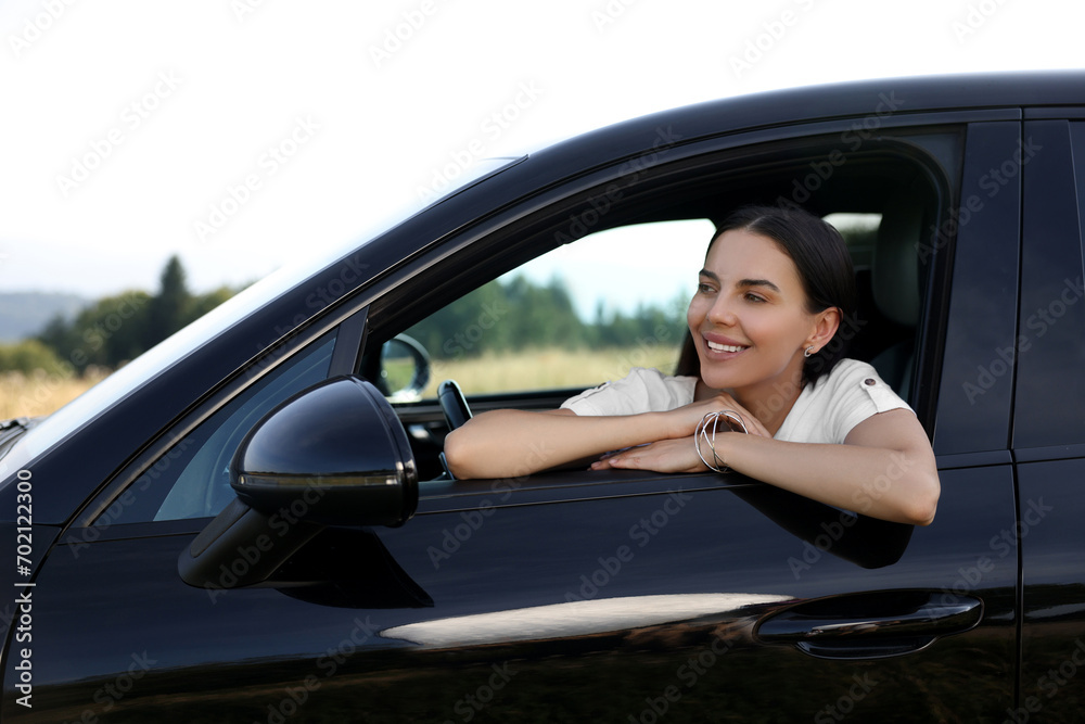 Enjoying trip. Portrait of beautiful happy woman in car, view from outside