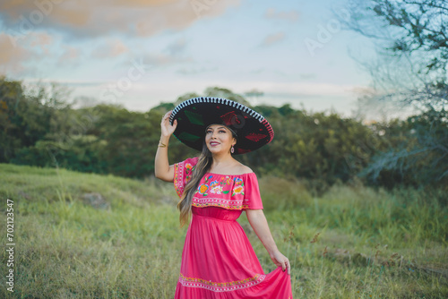 Mexican woman wearing traditional hat and dress. Portrait in a country setting.