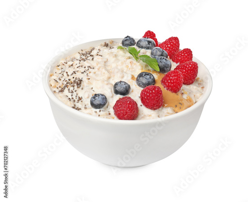 Tasty boiled oatmeal with berries, chia seeds and peanut butter in bowl isolated on white