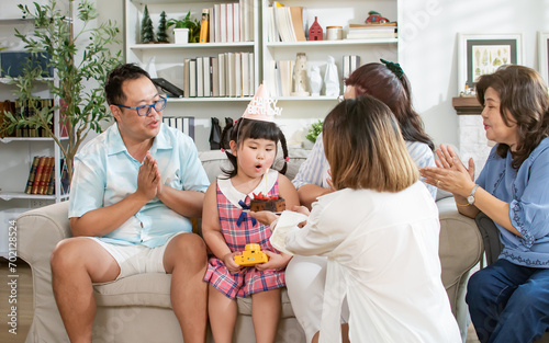 Wallpaper Mural Asian little girl wearing birthday hat, blowing candle of surprising cake, having happy time with family together, sitting in cozy living room at home. Party, Real Estate, Interior Concept. Torontodigital.ca