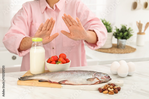 Woman suffering from food allergies refusing eat different fresh products at light table indoors, closeup photo