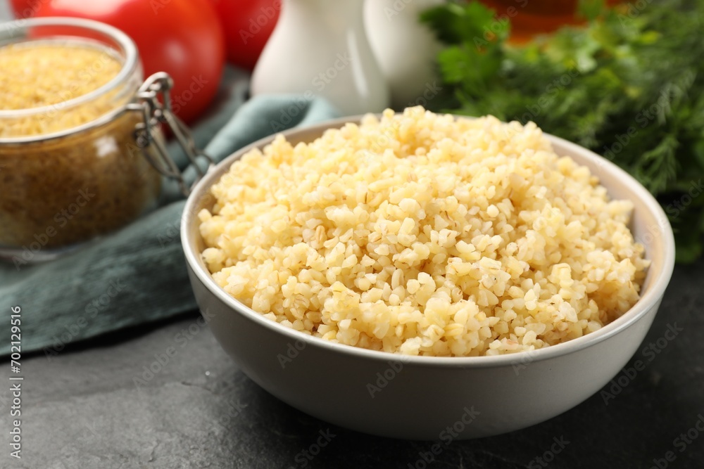 Delicious bulgur in bowl on black table, closeup Delicious bulgur in bowl on black table, closeup