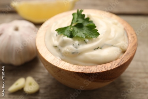 Tasty sauce with garlic and parsley on wooden table, closeup