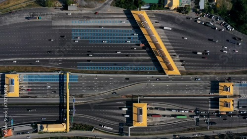 Timelapse aerial view of expressway toll gate and multi-lane road with fast-moving vehicles. Urban transport infrastructure and traffic network.