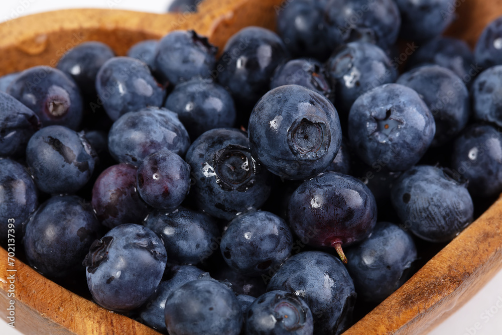 Blueberries in a wooden plate on a white background. Blueberries in a wooden plate on a white background.