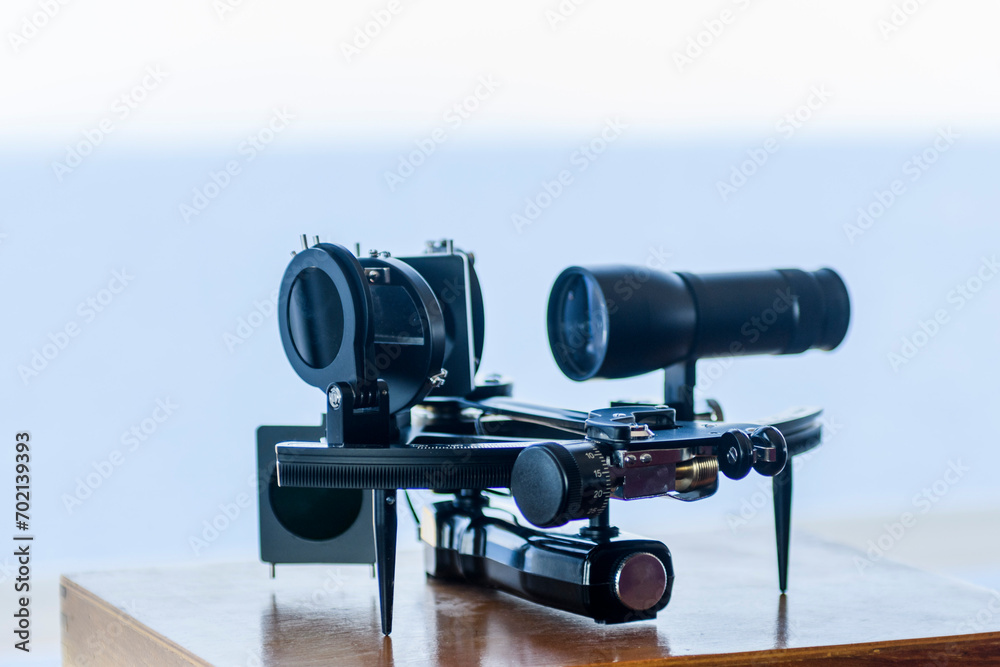 Nautical black sextant placed on wooden box in navigational bridge. Navigational equipment. Celestial navigation.