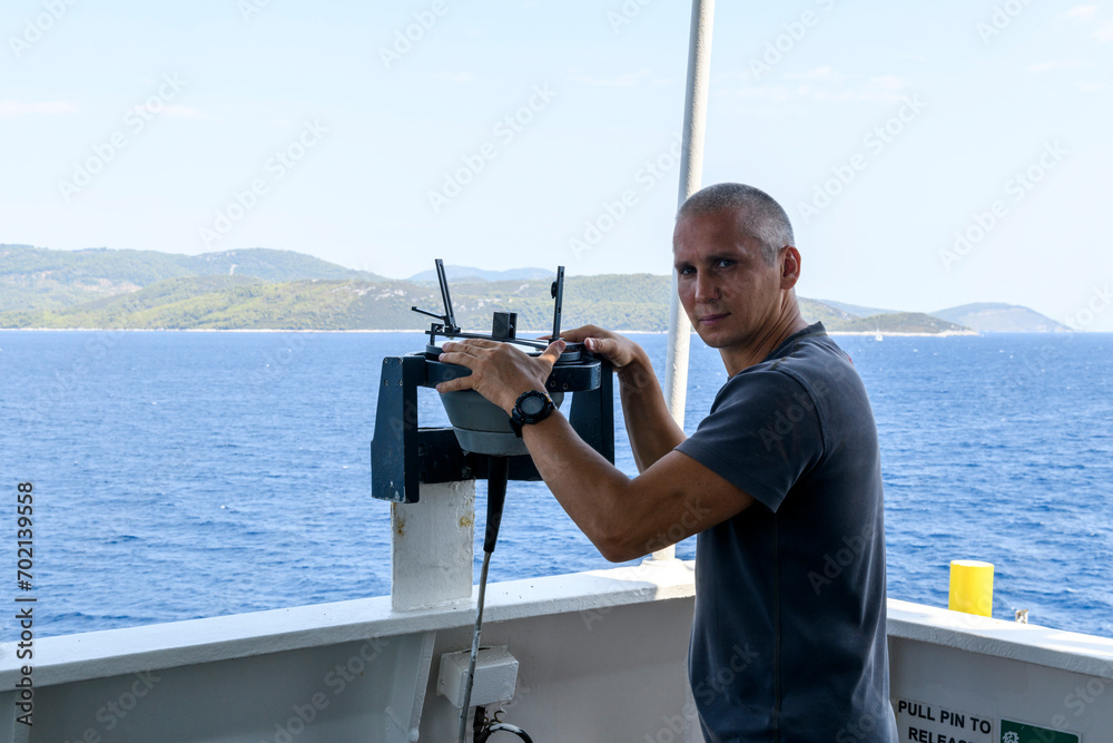 Navigational officer taking bearing with azimuth ring on gyro compass on the wing of navigational bridge. Navigational equipment usage. Observations. Navigational officer taking bearing with azimuth ring on gyro compass on the wing of navigational bridge. Navigational equipment usage. Observations.