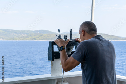 Navigational officer taking bearing with azimuth ring on gyro compass on the wing of navigational bridge. Navigational equipment usage. Observations.