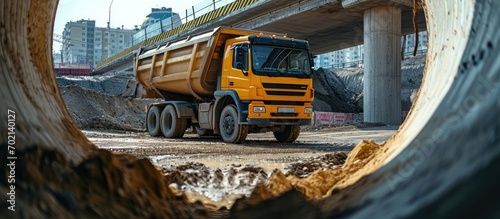 A large dump truck unloads rubble or gravel at a construction site Car tonar for transportation of heavy bulk cargo Providing the construction site with materials View from a large concrete pip photo