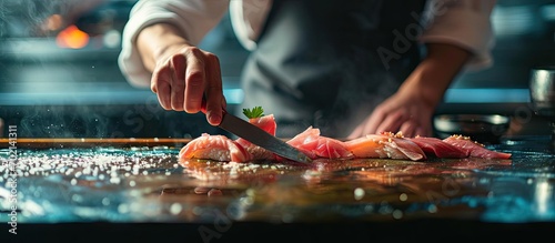 Close up Professional sushi chef hand using knife cutting Otoro Tuna belly part sashimi prepare to make perfect sushi with precision and confidence. with copy space image