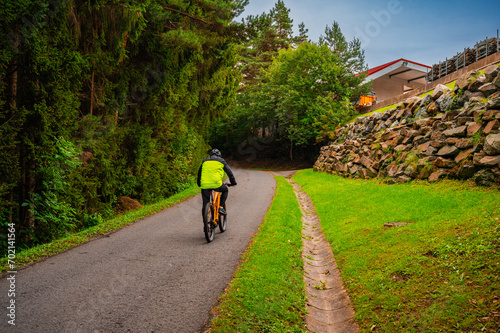 Asphalt way with bicyclists near forest. Calm background.