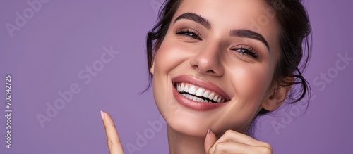 dental health beauty hygiene and people concept close up of smiling woman face pointing to teeth over violet background. with copy space image. Place for adding text or design photo