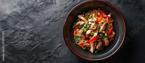 Asian noodles with chicken vegetables in bowl Asian style dinner Chinese or Japanese noodles Glass noodles stir fry with chicken carrots and onions Top view. with copy space image