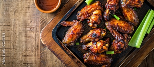 crispy barbecue chicken wings with celery on wooden serving tray. with copy space image. Place for adding text or design