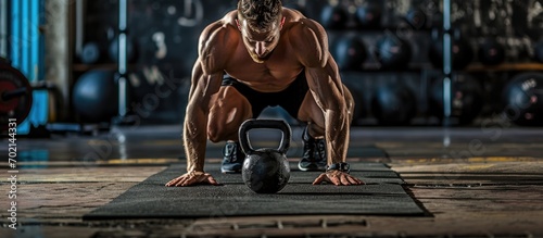 Determined shirtless muscular man doing push ups with kettle bells in the gym. with copy space image. Place for adding text or design