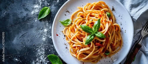 A picture of Italian pasta with red pepper pesto served on a white plate and decorated with basil. with copy space image. Place for adding text or design