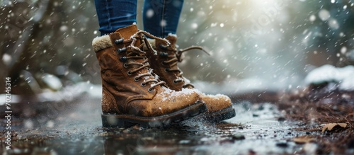 A woman applies the spray to brown nubuck women s winter boots Water repellent care for shoes renewal and preservation of color. with copy space image. Place for adding text or design photo
