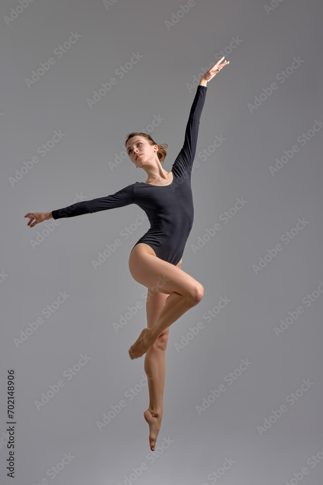 climactic pose of a live performance.coordination and concentration.freedom gorgeous ballet dancer in black swimsuit working out at studio hobby, lifestyle full length shot, isolated grey background