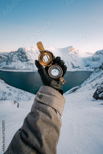 Person in snow covered mountains looking at a compass and checking directions (ID: 702150171)