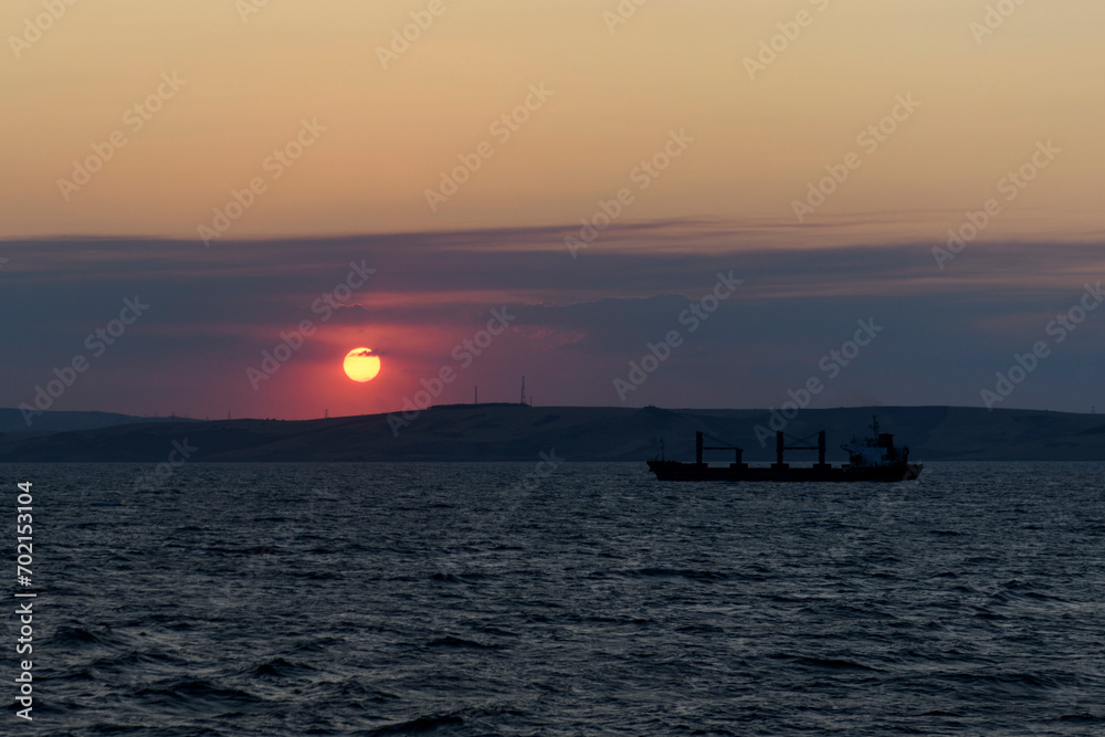 Fototapeta premium Cargo vessel at sea. Bulk carrier. Dry cargo ship at sunset.