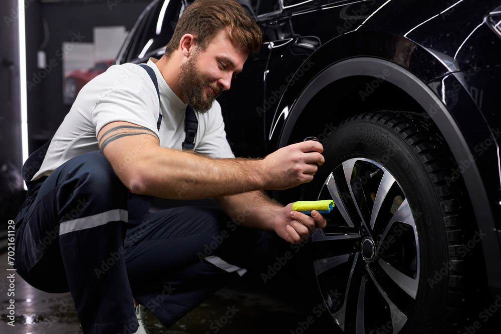 Professional Auto Mechanic Repair Man Using Liquid Oil For Lubricating Car Wheels In Auto Service,Side View Professional Auto Mechanic Repair Man Using Liquid Oil For Lubricating Car Wheels In Auto Service,Side View