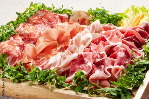 Tray of delicious mixed Italian prosciutto hams and salami with lettuce