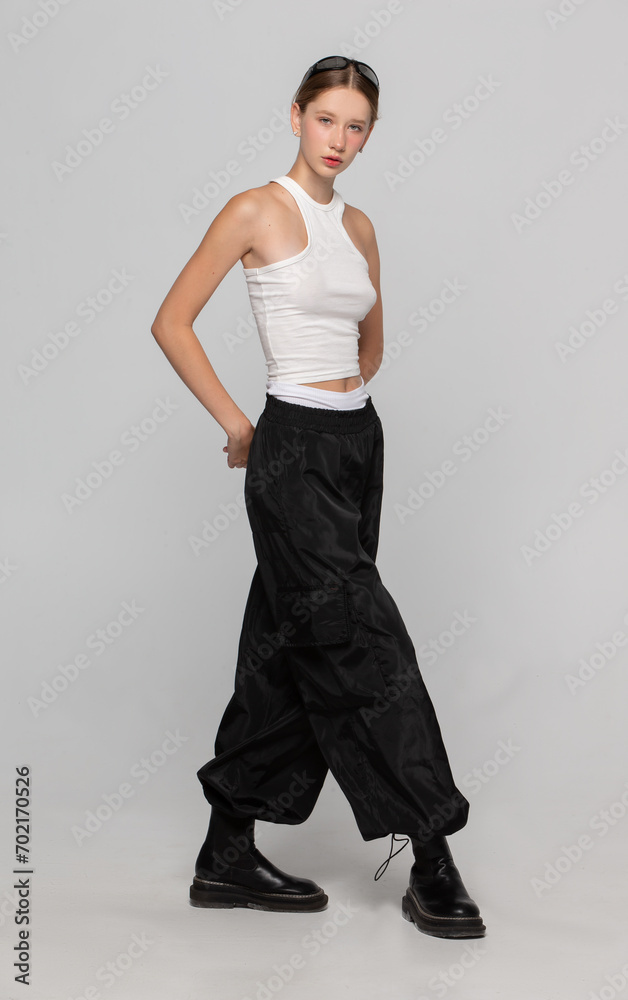 Beautiful girl in a white T-shirt and black fashionable pants on a gray background. Beautiful girl in a white T-shirt and black fashionable pants on a gray background.