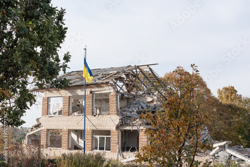 Fragment of a building destroyed by artillery. The flag of Ukraine hangs on the flagpole (concept: freedom)