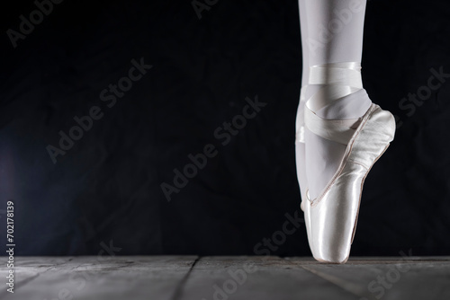 detail of female ballet dancer's foot in ballet position with pointe shoe in front of dark background with free space on the left side photo