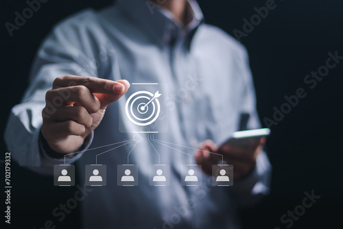 Customer relationship management concept. Businessman holding target icon linked with human icons for customer focus group. Data exchanges development and customer service. photo