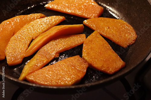 Frying pan with tasty roasted pumpkin pieces on the stove photo