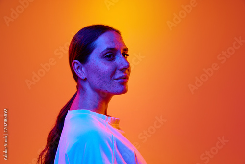 Side view portrait of young attractive lady looking away against gradient orange-yellow background with copy space for text. Concept of beauty, youth, human emotions, self-expression, lifestyle. Ad