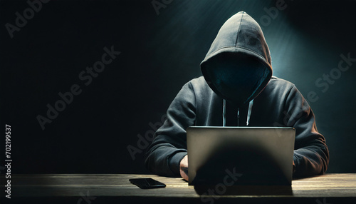 The dark web in a foreground hooded hacker with laptop at dark room.copy space. concept of business security and internet network data security.