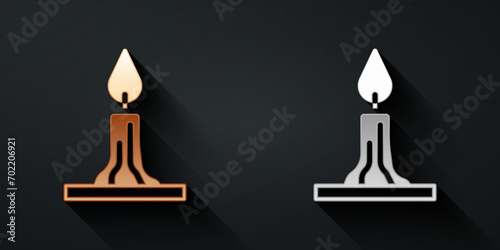 Gold and silver Burning candle in candlestick icon isolated on black background. Cylindrical candle stick with burning flame. Long shadow style. Vector