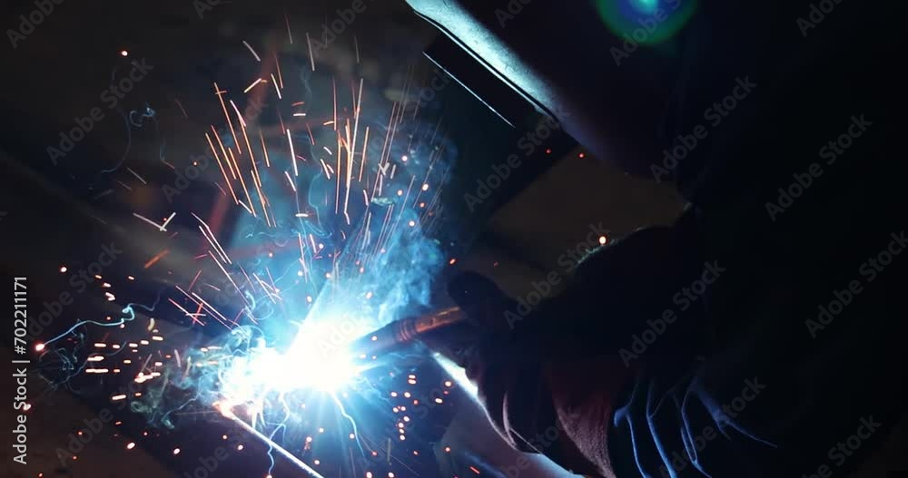 Welder at work in metal industry, welding metal construction. Close-up shot lots of sparks in the factory Welder at work in metal industry, welding metal construction. Close-up shot lots of sparks in the factory