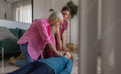 Emergency help for an unconscious woman lying on the floor receiving emergency CPR first aid. Health care and insurance concept photo