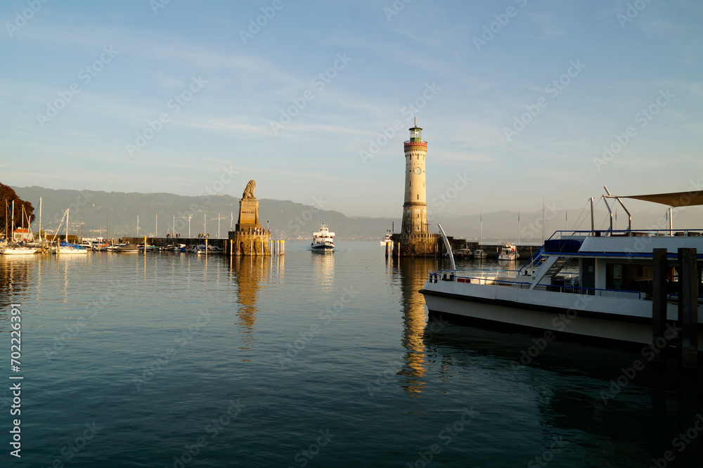 sunlit harbour and beacon of Lindau on tranquil lake Constance (lake Bodensee) with the Alps in the background on a sunny and warm evening in October (Lindau, Germany)	