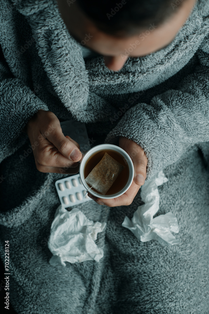 ill man in a house robe warming up with a tea