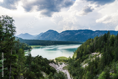 Sylvensteinstausee in the bavarian Alps in summer with a thunderstorm coming and forest in the foreground