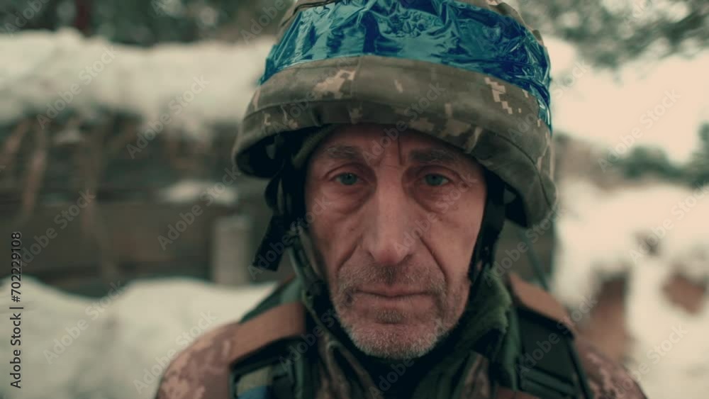 Close-up of an elderly Ukrainian soldier in military uniform and helmet. A Ukrainian soldier in a snowy trench. Close-up of an elderly Ukrainian soldier in military uniform and helmet. A Ukrainian soldier in a snowy trench.
