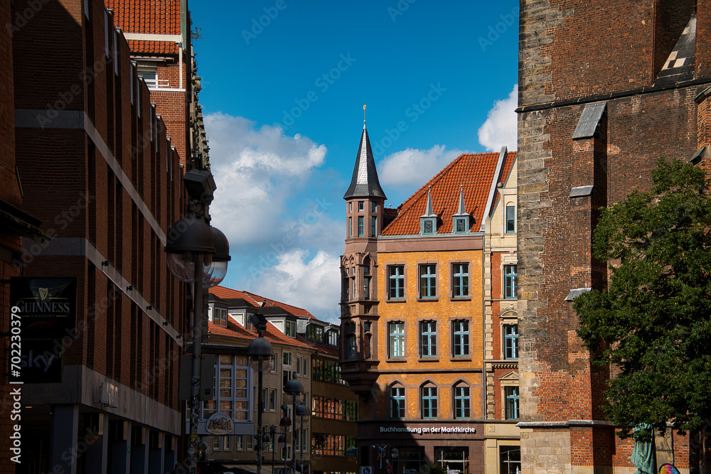 Blick in eine Altstadt mit historischen Hausfassaden und Kirchturm vor blauem Himmel